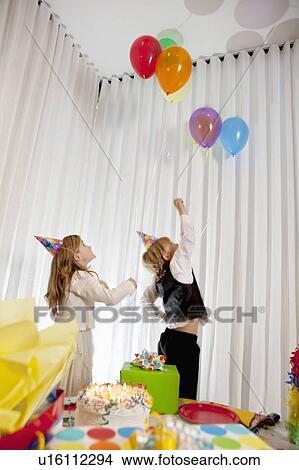 Picture - Brother and sister catching helium party balloon. Fotosearch