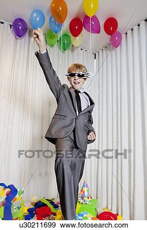 Cheerful young boy with raised fist in birthday party View Large Photo Image Stock Photo - Cheerful young boy with raised fist in birthday party. Fotosearch