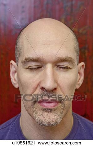 Stock Image - Close-up of a mature man with eye closed. Fotosearch