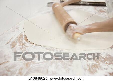 Stock Photography - Close-up of male baker's hands with rolling pin on dough in bakery. Fotosearch