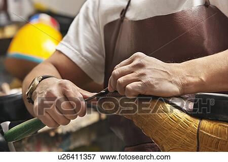 Stock Photo - Close-up of shoemaker's hands working on shoe sole in workshop. Fotosearch