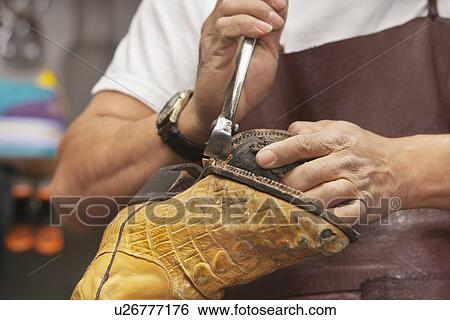 Stock Photograph - Cropped image of skilled shoemaker cutting shoe sole. Fotosearch