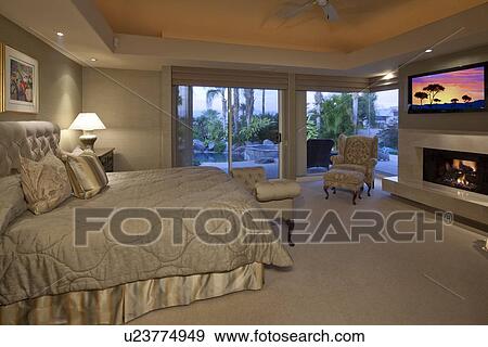 Flat Screen Television In Niche Above Fireplace In Master Bedroom