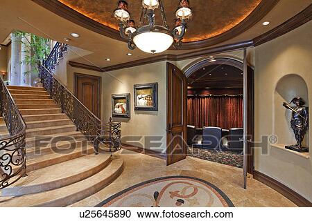 Stock Image - Hallway with stairway and open door in luxury mansion. Fotosearch
