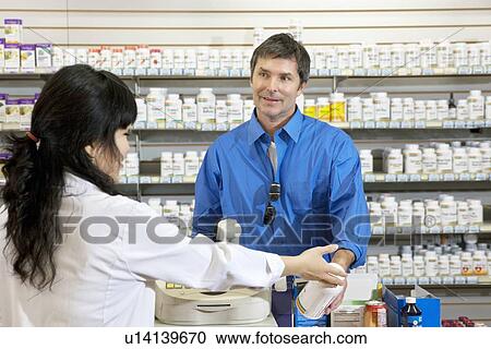 Happy mature man buying pills from female employee in drugstore View Large Photo Image Stock Image - Happy mature man buying pills from female employee in drugstore. Fotosearch
