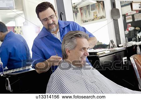 Stock Photograph - Happy mature man getting a haircut in barbershop. Fotosearch