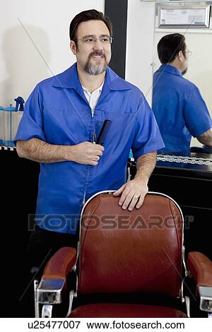 Stock Photo - Happy mature man with comb in barbershop. Fotosearch