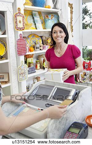 Picture - Happy mid adult customer paying for cake in cafe. Fotosearch