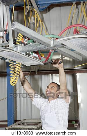 Happy worker adjusting machinery in factory View Large Photo Image Stock Image - Happy worker adjusting machinery in factory. Fotosearch