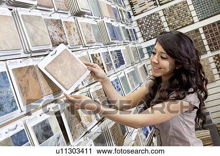 Stock Image - Happy young store clerk arranging samples in display. Fotosearch