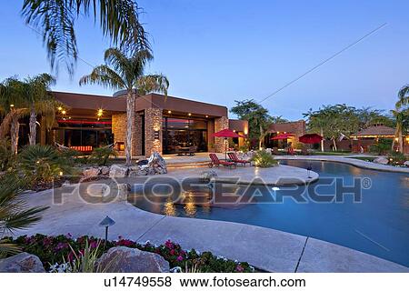 Stock Photo - Luxurious villa with swimming pool at dusk. Fotosearch