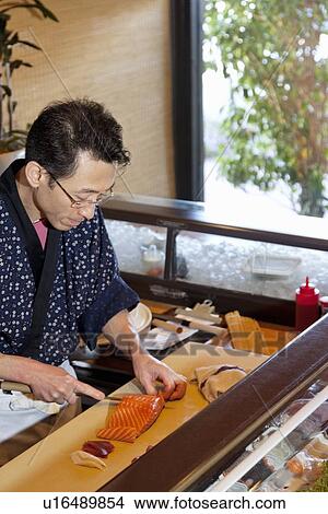 Mature Asian chef cutting fish in restaurant View Large Photo Image Picture - Mature Asian chef cutting fish in restaurant. Fotosearch