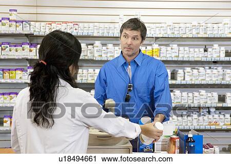 Mature man buying pills from female employee in drugstore View Large Photo Image Stock Image - Mature man buying pills from female employee in drugstore. Fotosearch