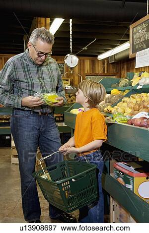 Mature man looking at produce with grandson in farmer's market View Large Photo Image Stock Photo - Mature man looking at produce with grandson in farmer's market. Fotosearch