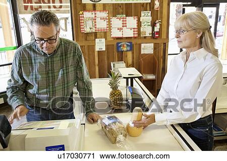 Mature owner with senior female customer at checkout counter in grocery market View Large Photo Image Stock Image - Mature owner with senior female customer at checkout counter in grocery market. Fotosearch