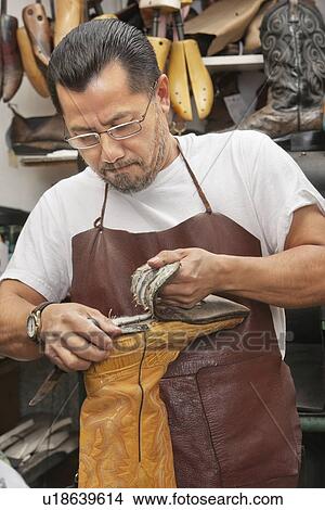 Mature shoemaker removing boot sole in shoe repair store View Large Photo Image Picture - Mature shoemaker removing boot sole in shoe repair store. Fotosearch