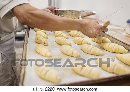 Stock Image - Midsection of baker making dough in bakery. Fotosearch