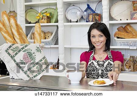 Portrait of a beautiful mid adult female employee with cup and pastry standing at counter in cafe View Large Photo Image Stock Photo - Portrait of a beautiful mid adult female employee with cup and pastry standing at counter in cafe. Fotosearch
