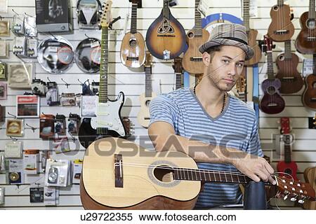 Portrait of a confident man restringing guitar in music store View Large Photo Image Stock Photography - Portrait of a confident man restringing guitar in music store. Fotosearch