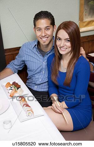 Stock Image - Portrait of a happy couple with Japanese cuisine. Fotosearch