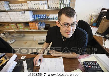 Portrait of a happy lighting shop owner sitting at desk in store View Large Photo Image Stock Photo - Portrait of a happy lighting shop owner sitting at desk in store. Fotosearch