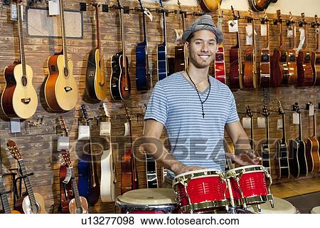 Portrait of a happy man playing bongo drums in music store View Large Photo Image Stock Photo - Portrait of a happy man playing bongo drums in music store. Fotosearch