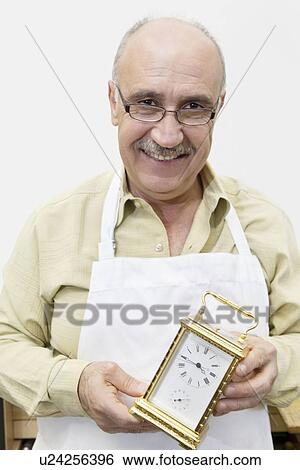 Portrait of a happy mature worker holding watch in workshop View Large Photo Image Stock Photograph - Portrait of a happy mature worker holding watch in workshop. Fotosearch