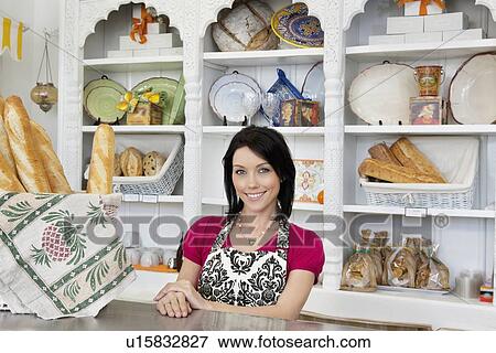 Stock Photo - Portrait of a happy mid adult employee standing at counter in cafe. Fotosearch