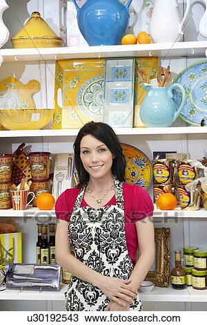 Stock Image - Portrait of a happy mid adult woman standing in cake shop. Fotosearch