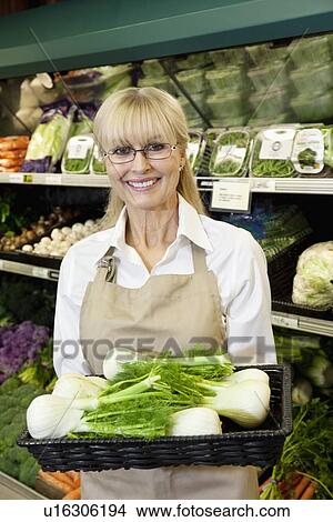 Portrait of a happy senior employee carrying bok choy in farmer's market View Large Photo Image Picture - Portrait of a happy senior employee carrying bok choy in farmer's market. Fotosearch