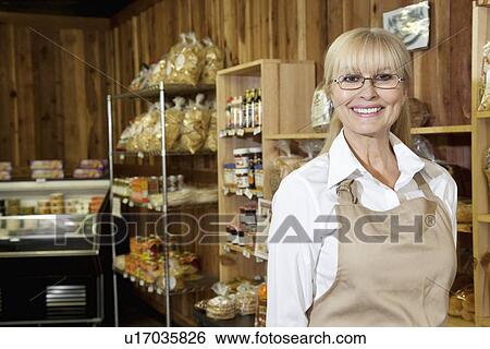 Portrait of a happy senior female employee in grocery store View Large Photo Image Stock Photograph - Portrait of a happy senior female employee in grocery store. Fotosearch