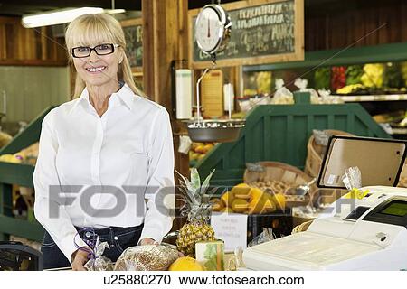Portrait of a happy senior woman standing by checkout counter View Large Photo Image Stock Image - Portrait of a happy senior woman standing by checkout counter. Fotosearch