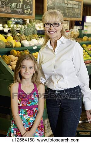 Stock Photo - Portrait of a happy senior woman with granddaughter in farmer's market. Fotosearch