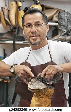 Portrait of a happy shoemaker cutting sole of footwear in workshop View Large Photo Image Stock Photograph - Portrait of a happy shoemaker cutting sole of footwear in workshop. Fotosearch