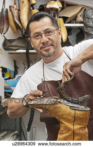 Stock Photo - Portrait of a happy shoemaker removing sole in workshop. Fotosearch