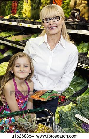 Picture - Portrait of a happy woman and girl in vegetable market. Fotosearch