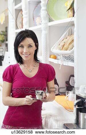 Portrait of a happy woman holding espresso coffee in cafe View Large Photo Image Stock Photo - Portrait of a happy woman holding espresso coffee in cafe. Fotosearch