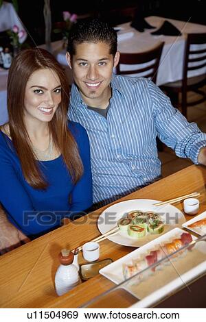 Portrait of a happy young couple in Japanese restaurant eating sushi View Large Photo Image Stock Photo - Portrait of a happy young couple in Japanese restaurant eating sushi. Fotosearch