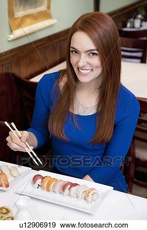 Portrait of a happy young woman eating sushi in Japanese restaurant View Large Photo Image Stock Photo - Portrait of a happy young woman eating sushi in Japanese restaurant. Fotosearch
