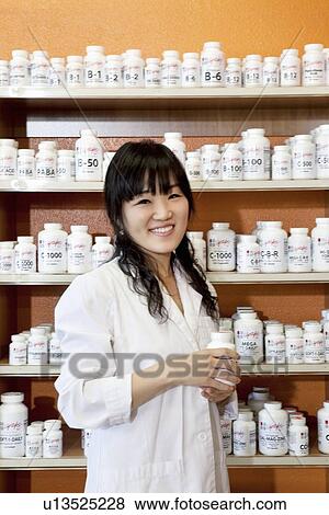 Portrait of a happy young woman with pill bottle in drugstore View Large Photo Image Stock Photo - Portrait of a happy young woman with pill bottle in drugstore. Fotosearch