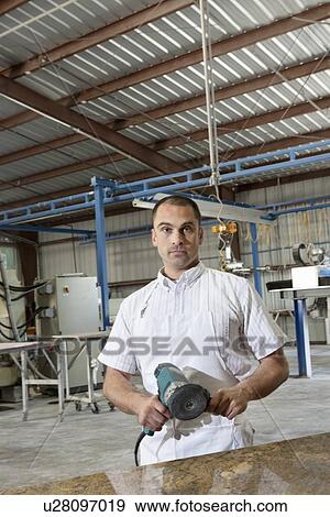 Portrait of a industrial factory worker holding electric saw View Large Photo Image Stock Photo - Portrait of a industrial factory worker holding electric saw. Fotosearch