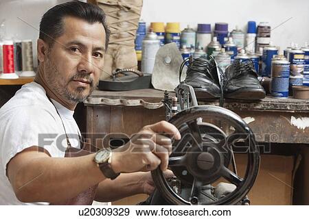 Stock Photo - Portrait of a mature cobbler with sewing machine in workshop. Fotosearch