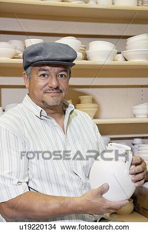 Portrait of a mature potter holding ceramic vase in workshop View Large Photo Image Picture - Portrait of a mature potter holding ceramic vase in workshop. Fotosearch