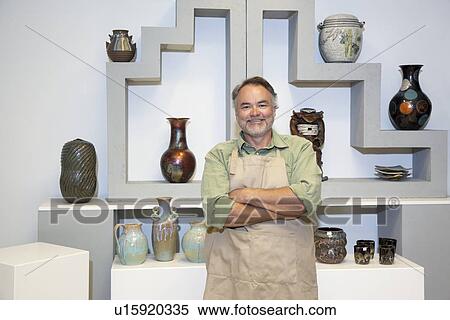 Portrait of a mature potter with arms crossed standing in front of clay vases in workshop View Large Photo Image Stock Photography - Portrait of a mature potter with arms crossed standing in front of clay vases in workshop. Fotosearch