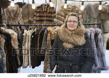 Stock Image - Portrait of a mature woman standing in front of fur stall. Fotosearch