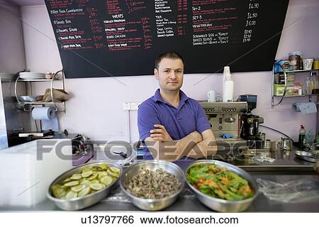 Portrait of a mid adult man standing behind display case with arms crossed in cafe View Large Photo Image Stock Photograph - Portrait of a mid adult man standing behind display case with arms crossed in cafe. Fotosearch