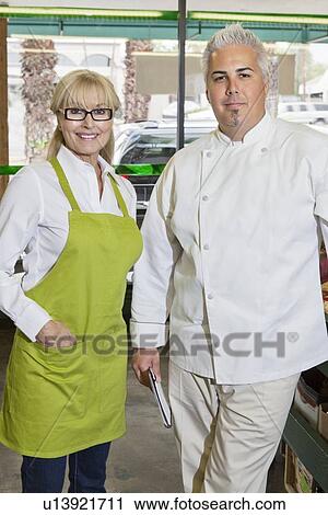 Stock Image - Portrait of a senior woman with mid adult chef in market. Fotosearch