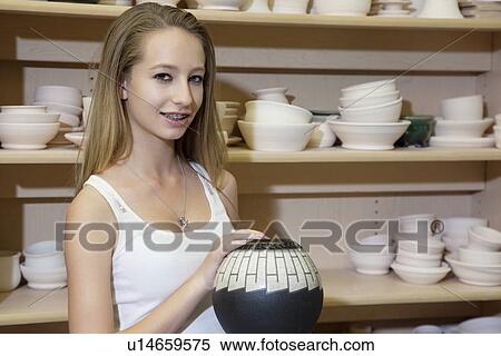 Stock Photography - Portrait of a teenage girl with vase in workshop. Fotosearch