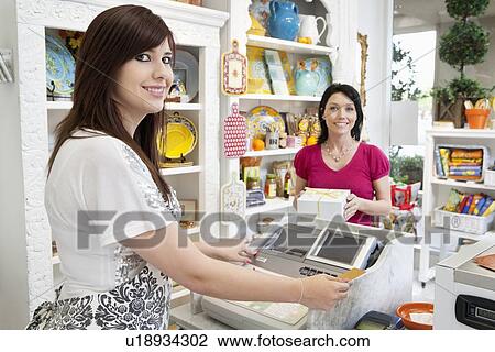 Portrait of a young caterer at checkout counter with female customer in background View Large Photo Image Stock Image - Portrait of a young caterer at checkout counter with female customer in background. Fotosearch