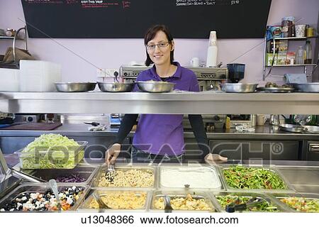 Portrait of a young female employee standing behind display case View Large Photo Image Stock Photograph - Portrait of a young female employee standing behind display case. Fotosearch